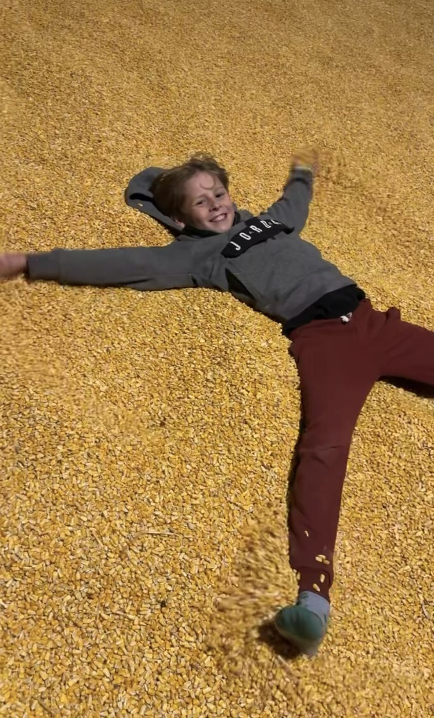 A kid making a corn angel in the corn pit